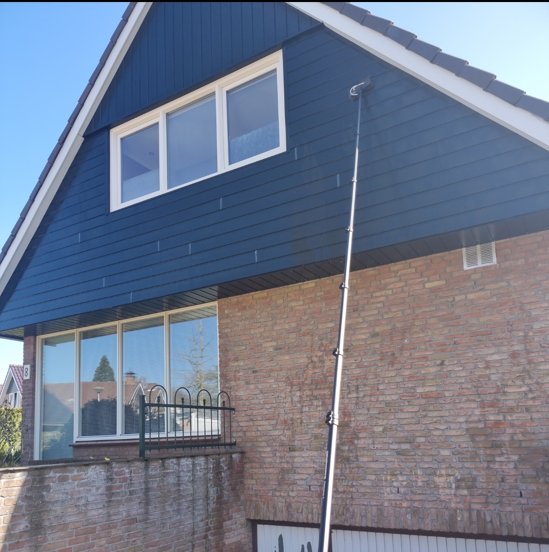 Telescopische waterborstel reinigt de dakkapelramen van een woning