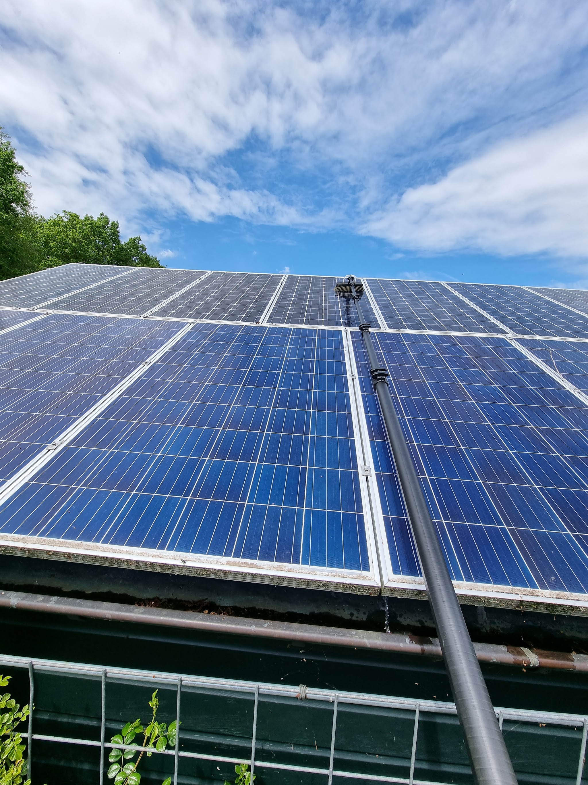 Zonnepanelen worden gereinigd met een waterborstel onder een blauwe lucht