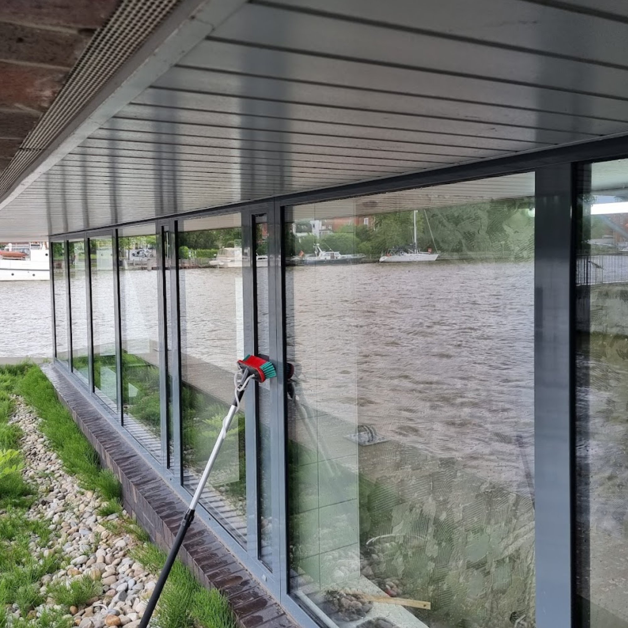Glazen gevel aan het water wordt gewassen met een waterborstel